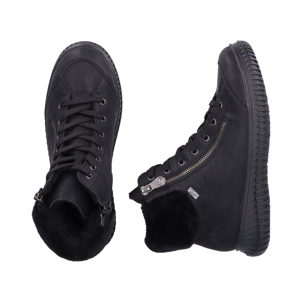 Two black high-top sneakers, one upright and one on its side, with laces and side zippers, showing fluffy black interior lining.