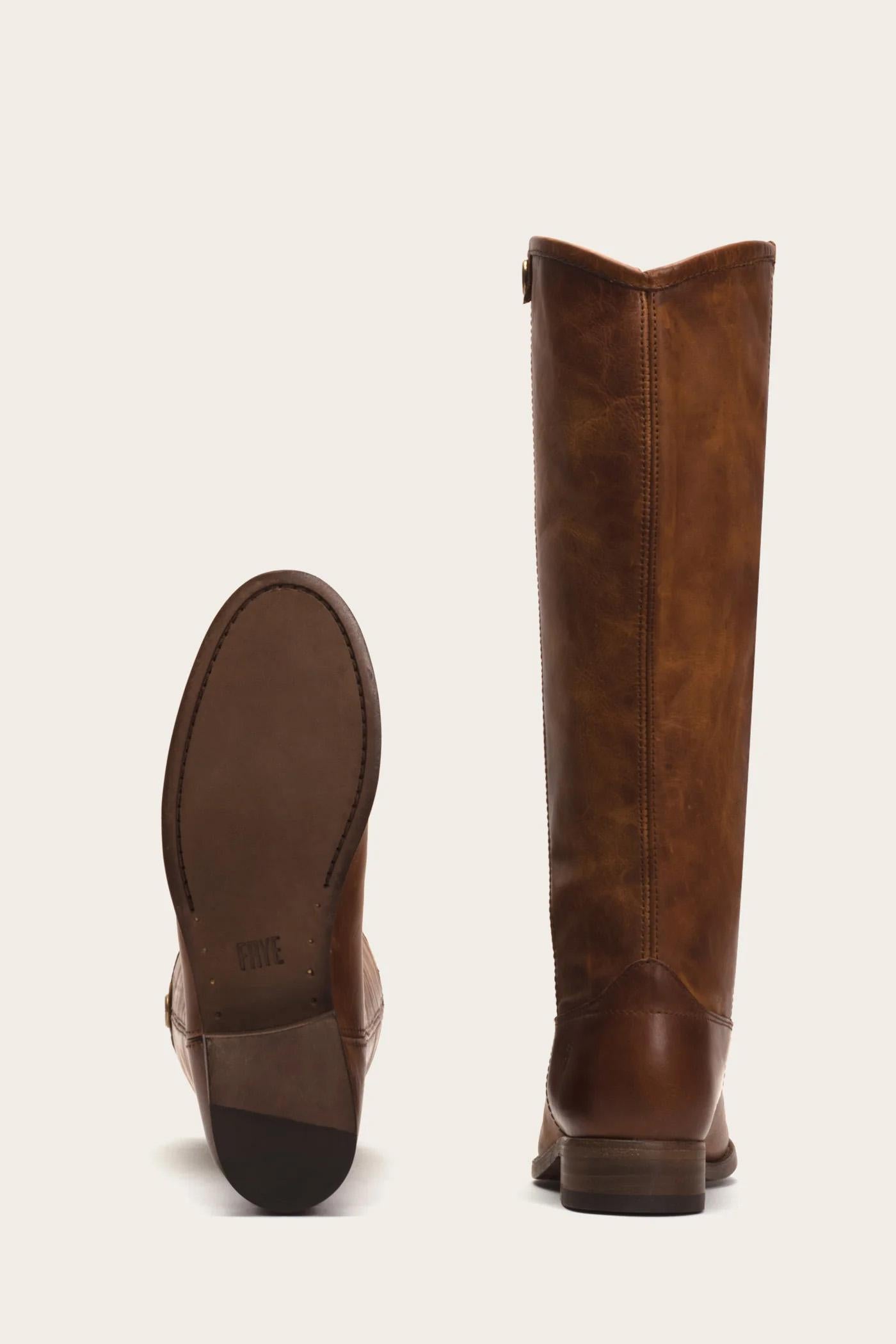 Two brown leather knee-high boots, one standing upright and the other positioned to show the sole.