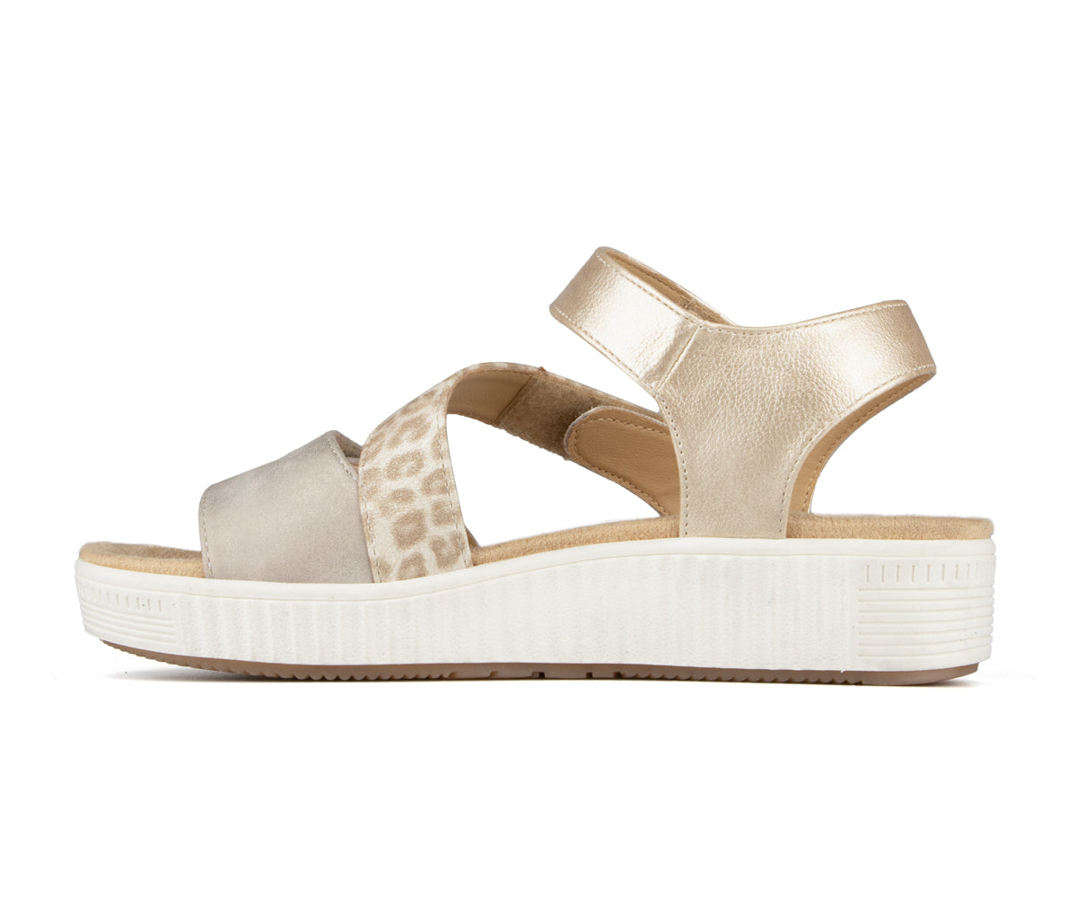 Side view of a women's beige sandal with cross leopard print, velcro ankle strap and white sole.