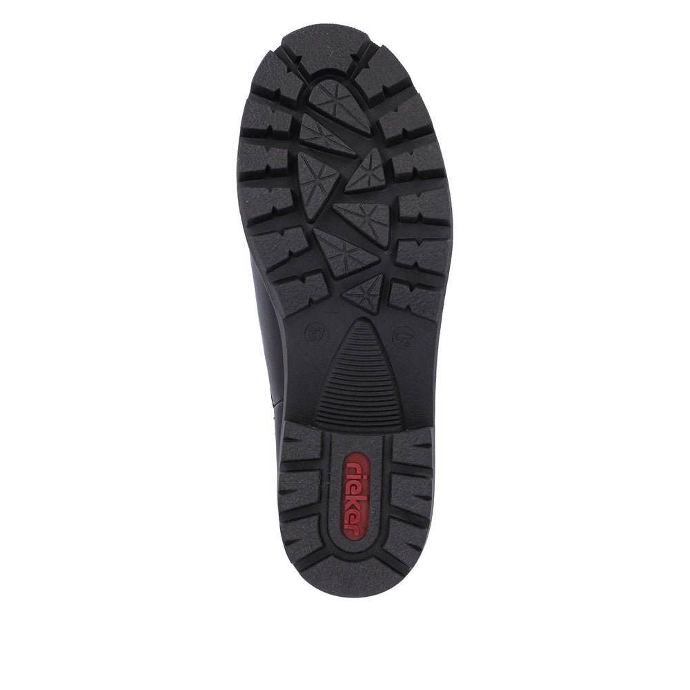 Black shoe sole with thick treads including triangles, parallel lines, and a red logo in the heel area.