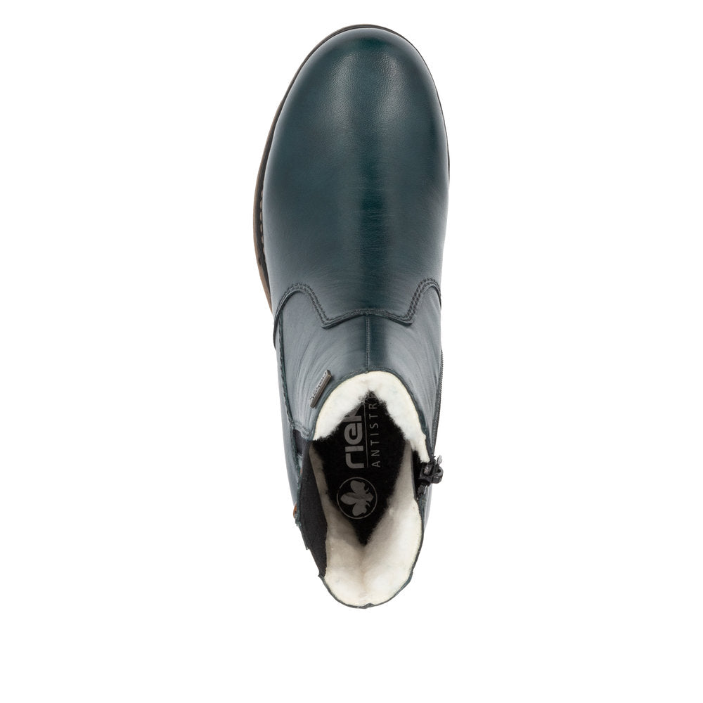 Top-down view of a blue, round-toed, zip-up boot with white fur lining, and the text "RIEKER ANTISTRESS" visible on the inner sole.