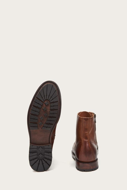 Two brown leather boots, one with sole visible, zipper on the side.