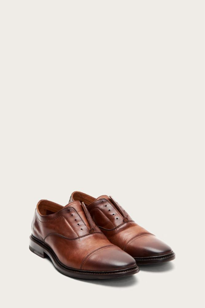 A pair of brown leather cap-toe dress shoes.