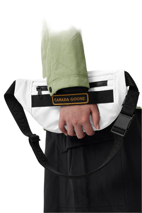 White belt bag with a black stripe across the center with a logo patch.
