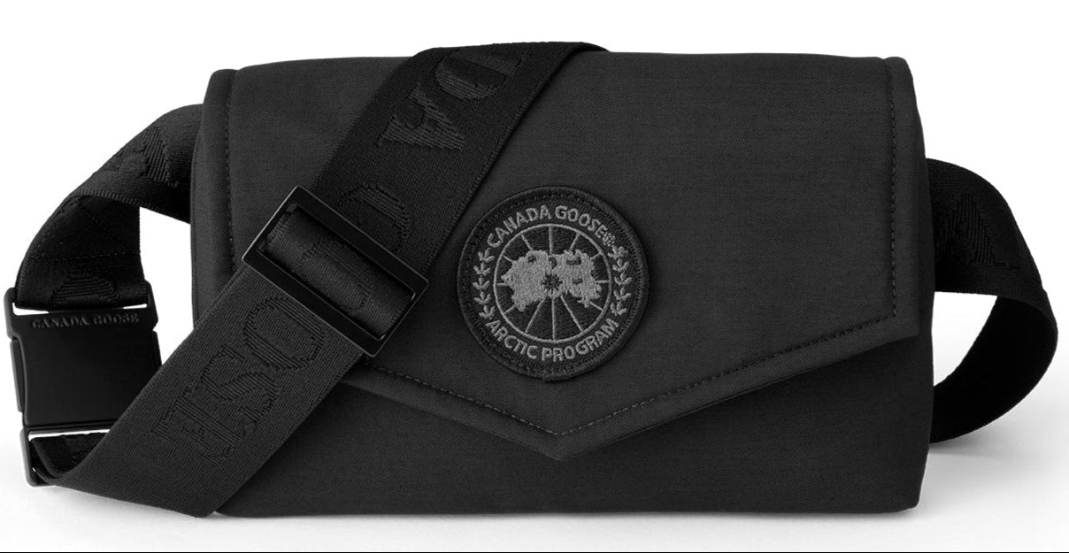 Black waist bag with visible shoulder strap and round logo patch reading "CANADA GOOSE ARCTIC PROGRAM".
