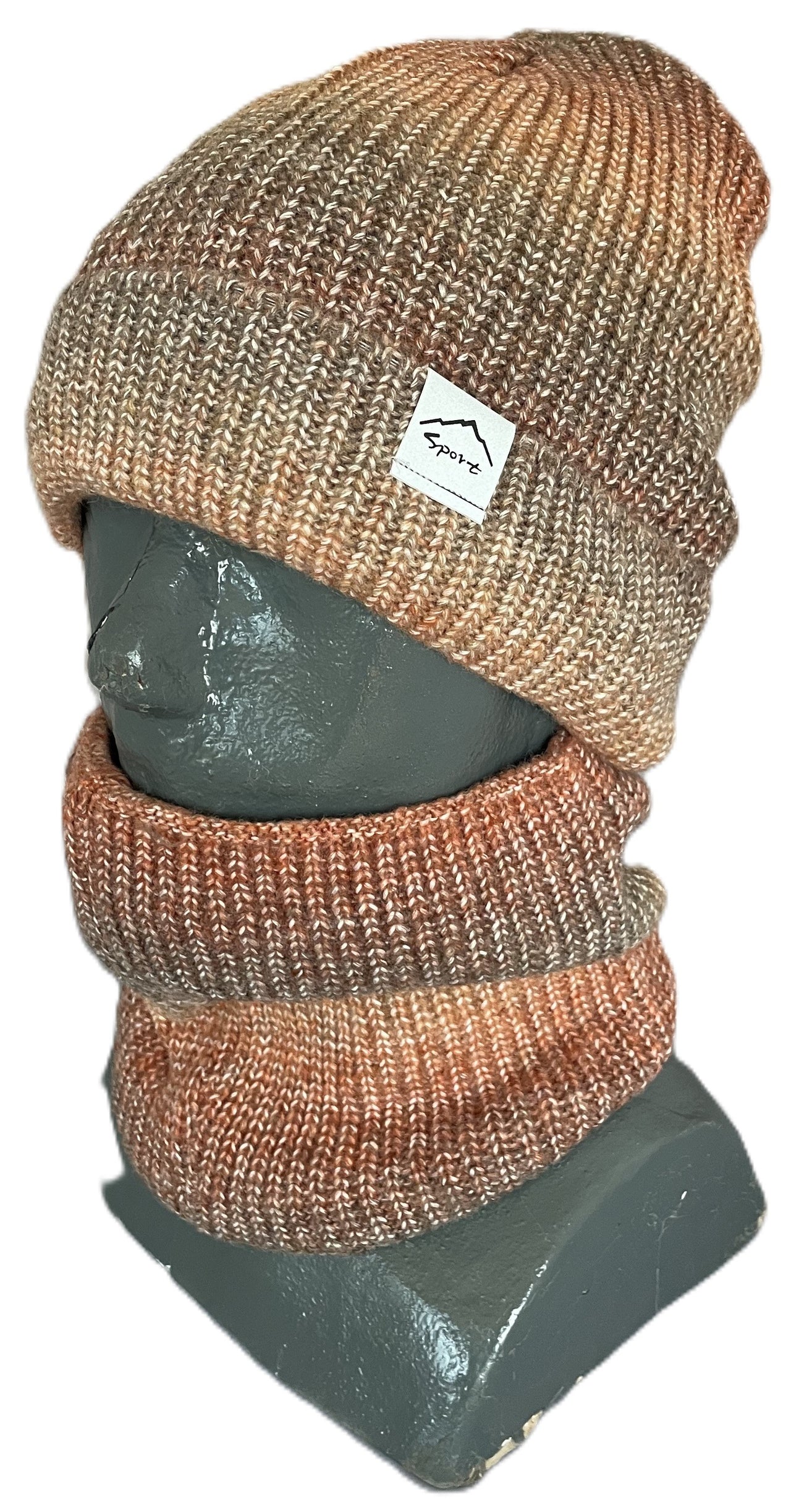 A ribbed knit beanie and matching neck warmer in a heathered, multi-tonal mix of brown, orange, and tan, shown on a gray mannequin bust with a small rectangular white tag on the beanie featuring a mountain graphic and text.