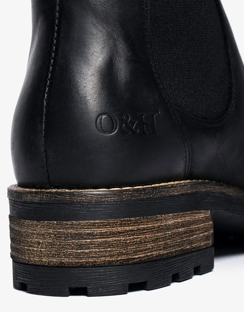 Close-up of the heel of a black leather boot showing a layered sole with "O&H" embossed on the ankle.