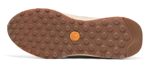The outsole of a shoe features small, round treads and a circular logo with a tree.
