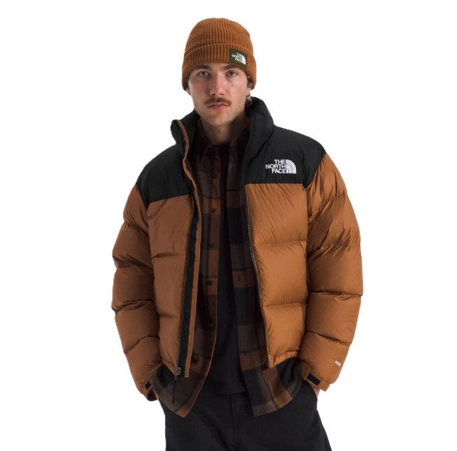 Man wearing a brown puffer jacket with black yoke and a matching beanie.