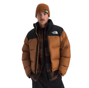 Man wearing a brown puffer jacket with black yoke and a matching beanie.