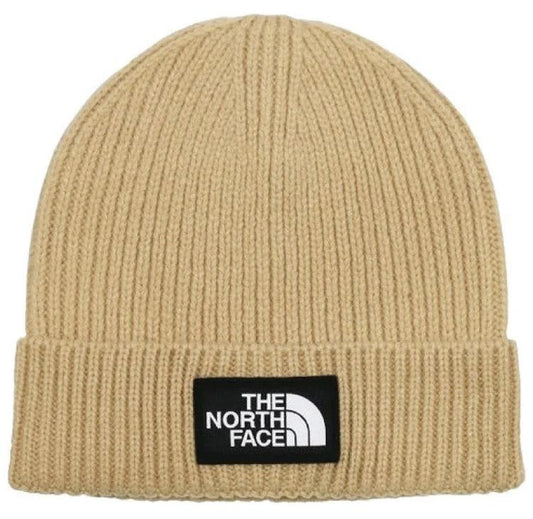 Ribbed tan beanie with a black tag displaying 'THE NORTH FACE' in white letters.