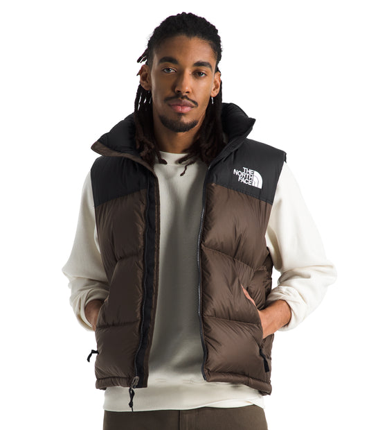 Man wearing a brown and black down vest with visible logo patch.