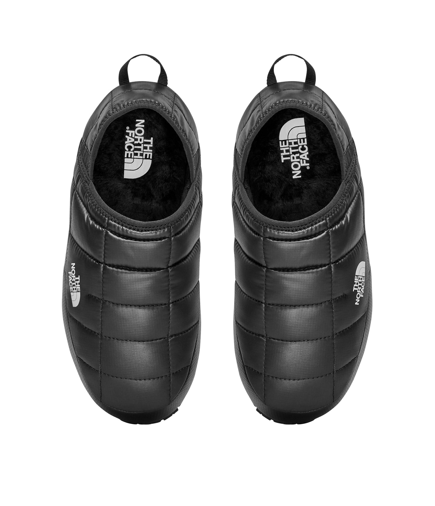 Overhead view of a pair of black quilted slip-on shoes with a loop at the heel.