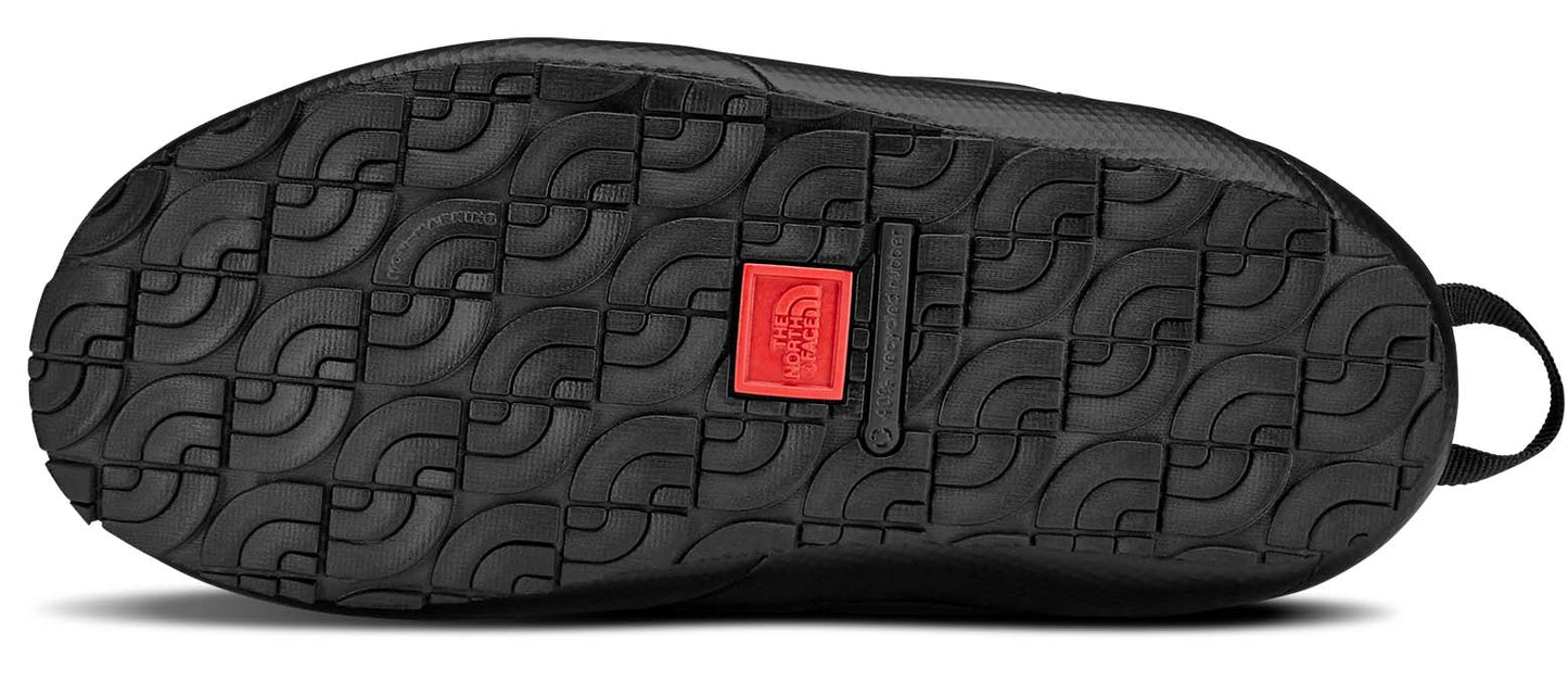 Bottom view of black slipper with curved tread and red logo.