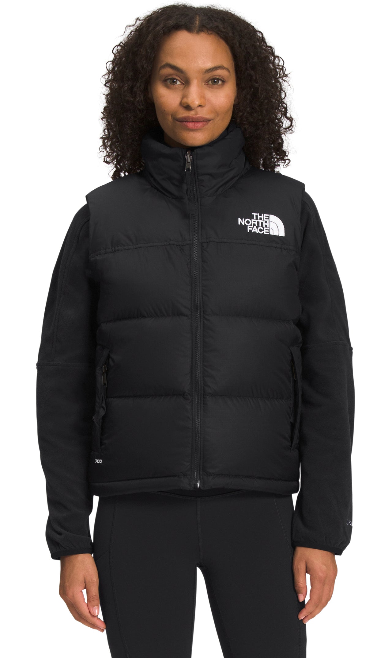 Woman wearing a black puffer vest with a white logo on the upper right.
