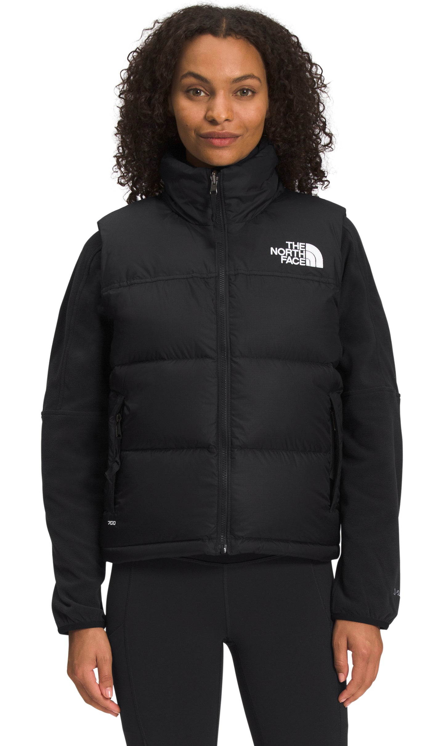 Woman wearing a black puffer vest with a white logo on the upper right.