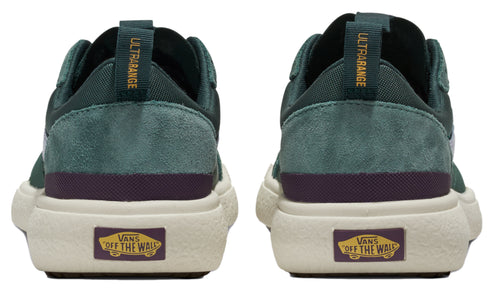 A pair of green shoes with a beige sole, purple accent, and a yellow square emblem saying "VANS OFF THE WALL" on the heel tab.