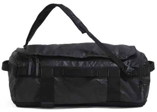 A black duffel bag with a shoulder strap is lying down.