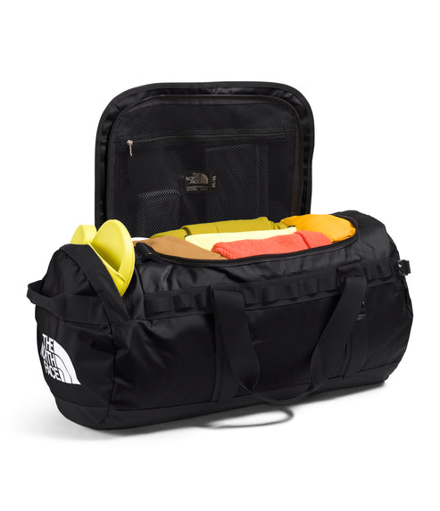 Black duffel bag open with clothing inside.