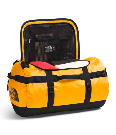 Yellow duffel bag with black straps and base; bag is open, revealing mesh pocket and clothing inside.