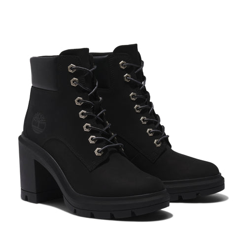 A pair of black, high-heeled, lace-up boots with a visible Timberland logo on the ankle.