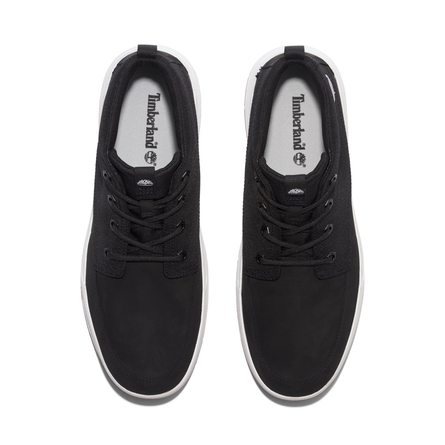 Overhead view of a pair of black canvas shoes with white soles and white interior with a Timberland logo.