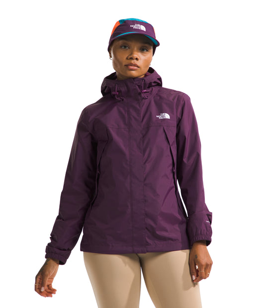 A woman in a plum colored jacket and tan pants, wearing a colorful hat.