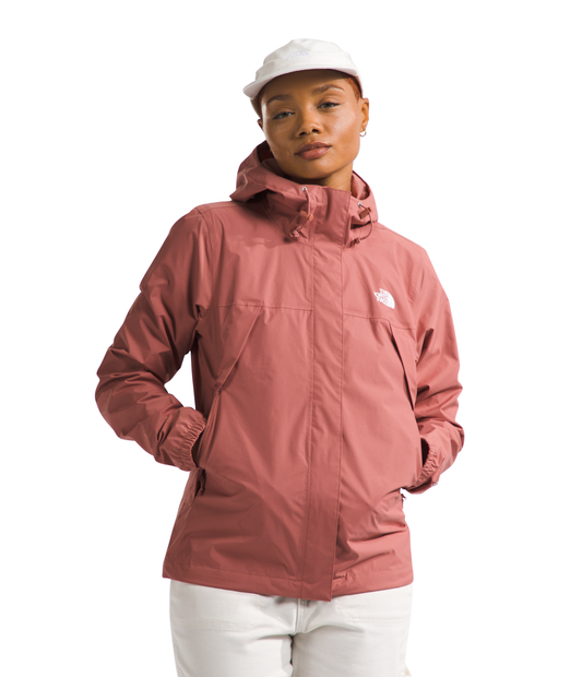 A woman wearing a pink hooded jacket with white pants and a white hat.