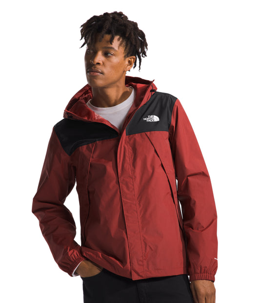 A man wears a red hooded jacket with a black upper chest and hood.