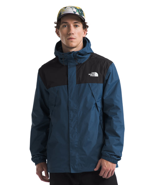 A man wearing a dark blue and black hooded rain jacket and a colorful hat.