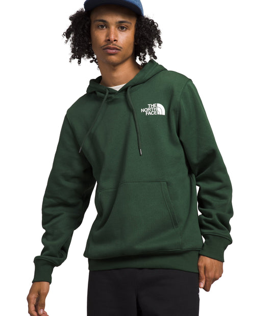 Person wearing a green hoodie with a logo on the upper-left chest, and a blue hat.