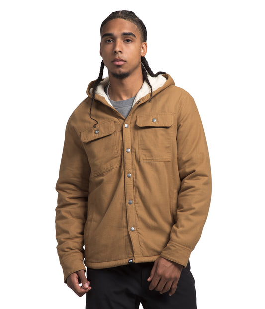 A man wearing a tan, hooded, button-down jacket with chest pockets.