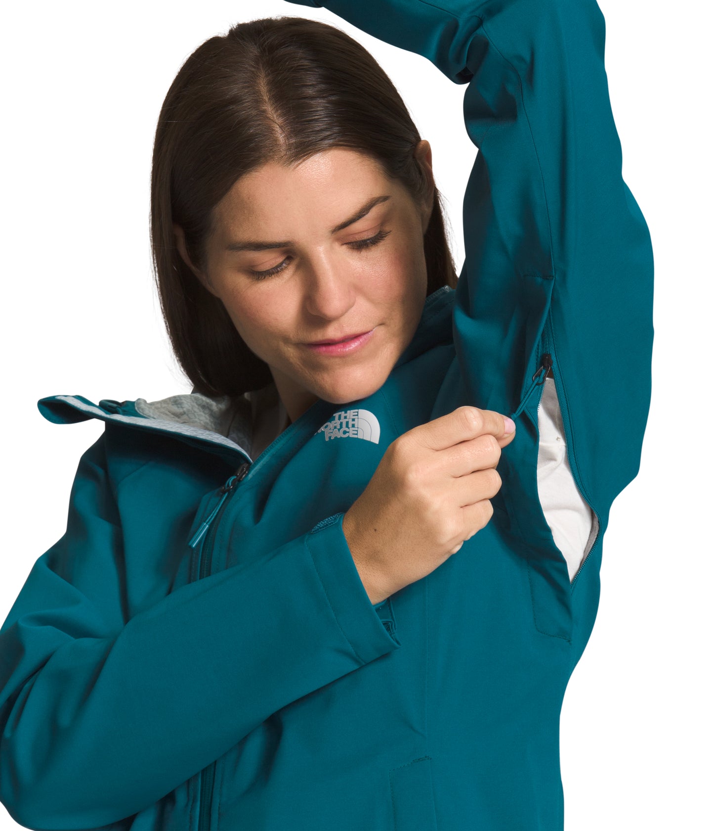 Woman in a teal waterproof jacket with pit zips and a white logo patch.