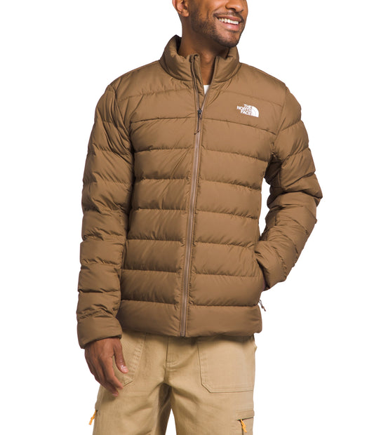 A man wearing a light brown, zip-up, quilted jacket and tan pants.