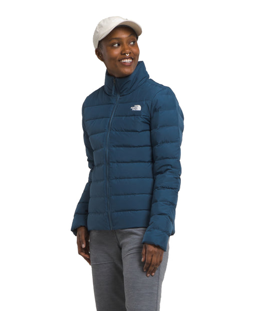 A person wearing a navy blue puffer jacket with matching pants and a white cap.
