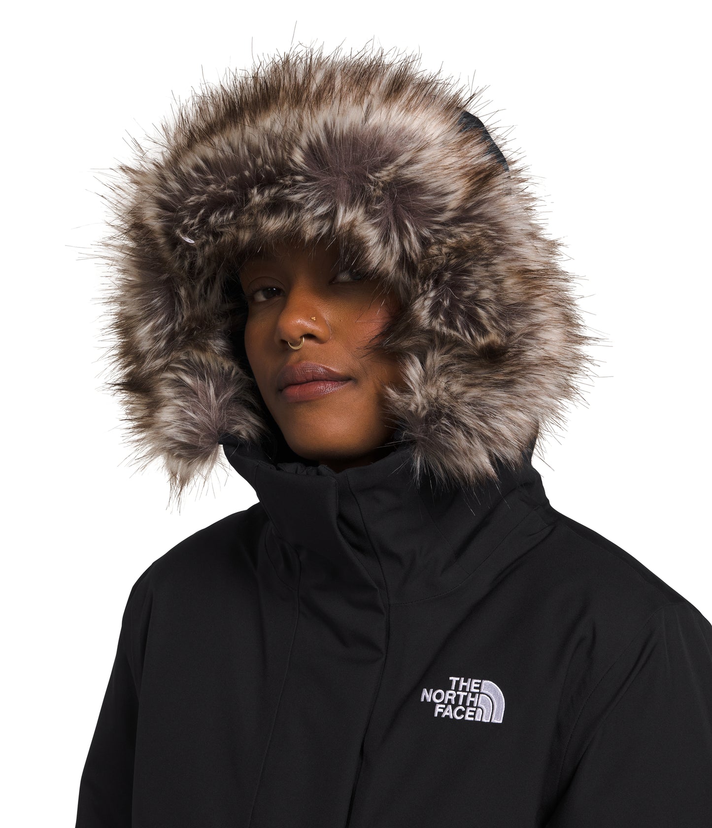 Close-up of a person wearing a black hooded winter coat with a large faux fur trim on the hood and the The North Face logo on the chest.