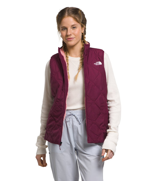 A woman in a maroon quilted vest over a cream-colored long-sleeved shirt, paired with light blue pants.
