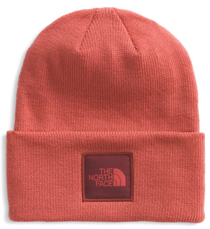 Close-up of a reddish-orange beanie with a square logo patch that says "THE NORTH FACE".