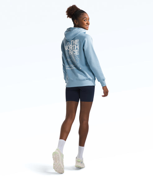 A woman wearing a light blue hoodie with "THE NORTH FACE" on the back and navy shorts, looking over her shoulder.