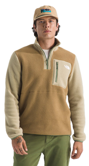 A person wearing a tan, half-zip fleece with tan sleeves, a front pocket with a zipper, green pants, and a matching hat.