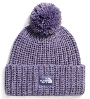 A purple, chunky-knit beanie featuring a thick ribbed cuff with a purple square patch displaying the words THE NORTH FACE and a half-dome logo in white, topped with a matching purple pom-pom.