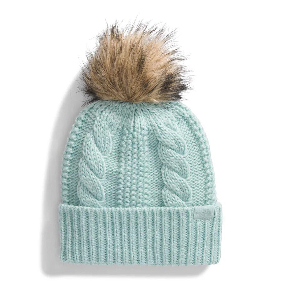Light blue knit beanie with cable-knit details and pompom on top.