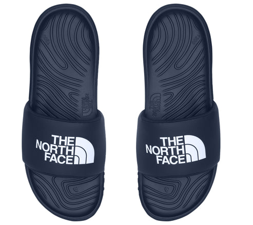 Top-down view of a pair of dark blue slide sandals, each with white "THE NORTH FACE" text on the upper band.