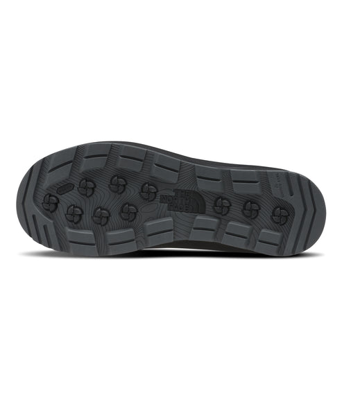 Close-up of a gray boot outsole with a textured pattern of geometric shapes, including circular and rectangular elements.
