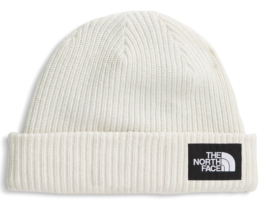 Close-fitting off-white knit hat with a black rectangular patch displaying the words 'THE NORTH FACE' stacked above a quarter circle shape.