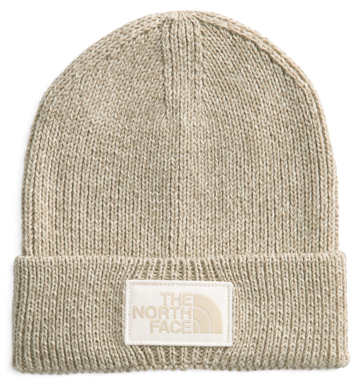 Knitted beige beanie with white rectangular patch with "THE NORTH FACE" lettering.