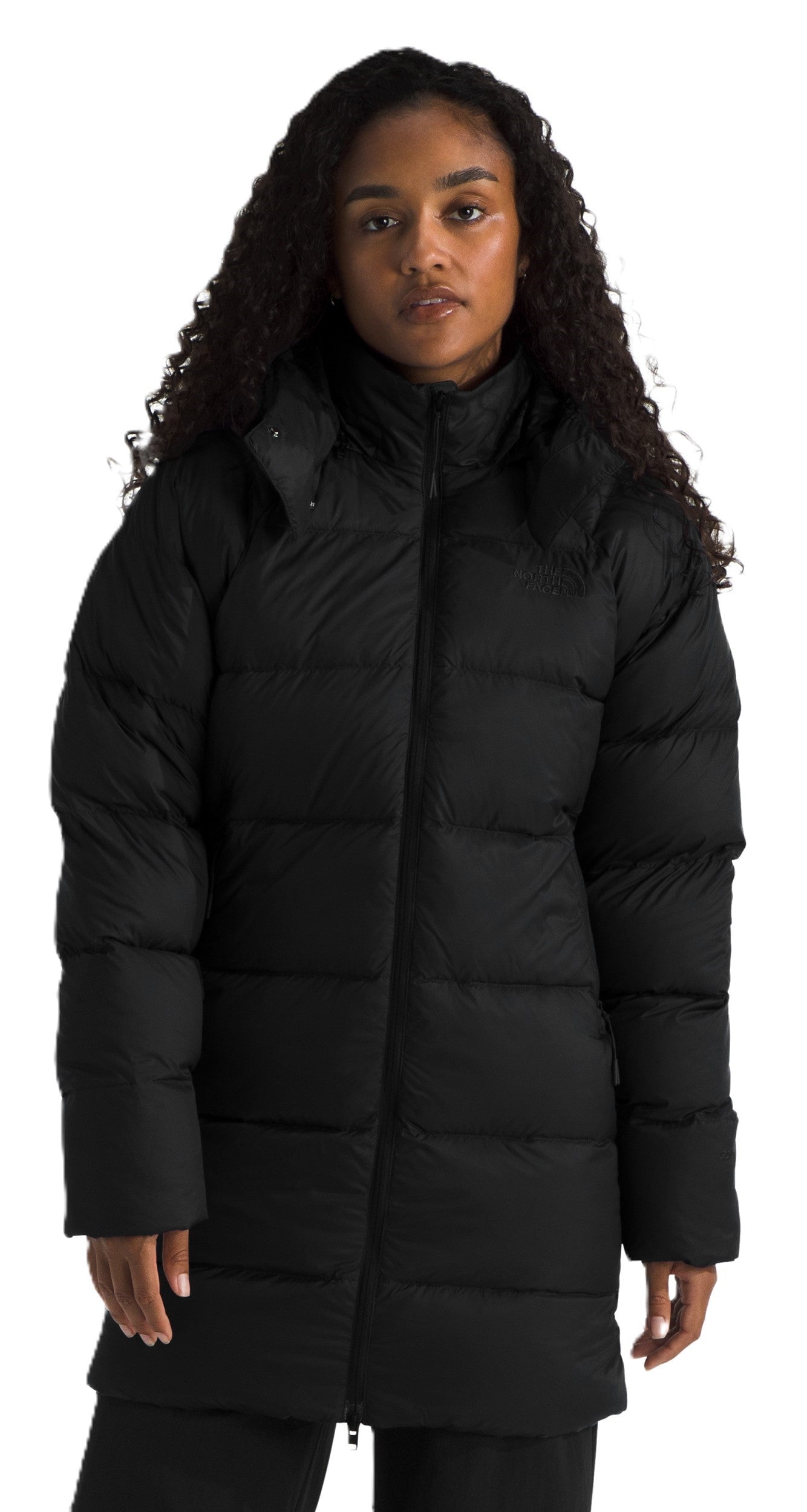A person wearing a long, black, puffy coat with a hood.