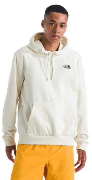 A light yellow hoodie on a person with a black logo on the upper right chest and a kangaroo pocket.