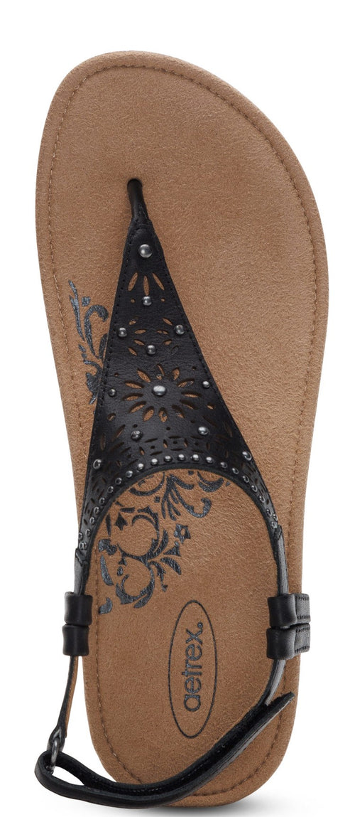 A sandal with black straps decorated with studs and laser cut-outs.