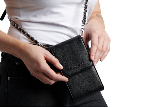 Person holding a black leather wallet-style phone case with silver chain strap.